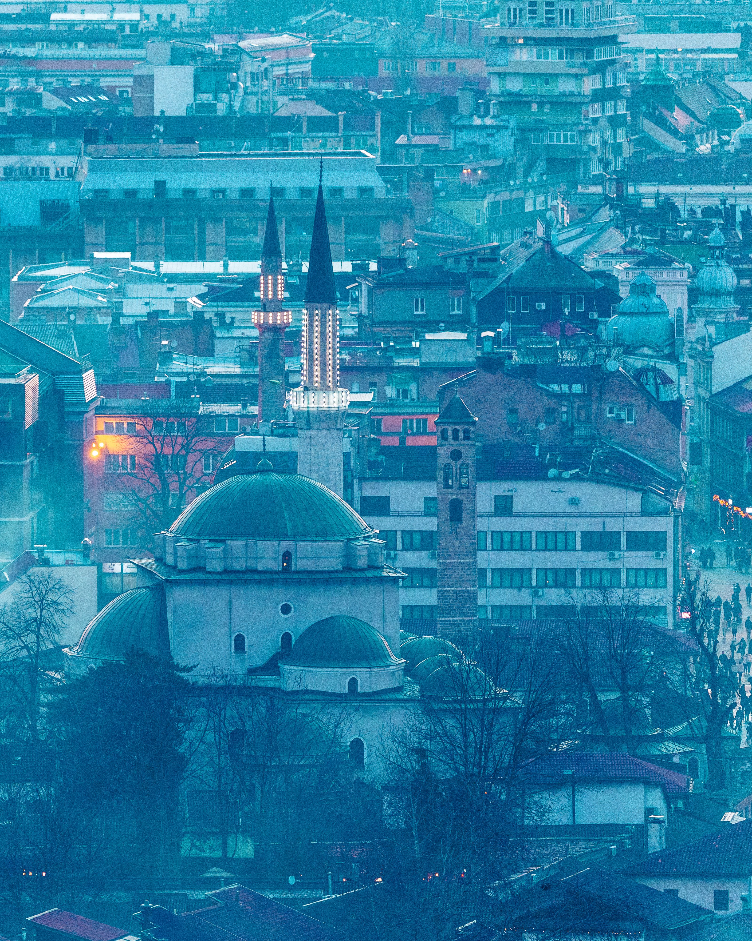 Aerial view of Sarajevo featuring the Gazi Husrev-beg Mosque surrounded by city architecture.