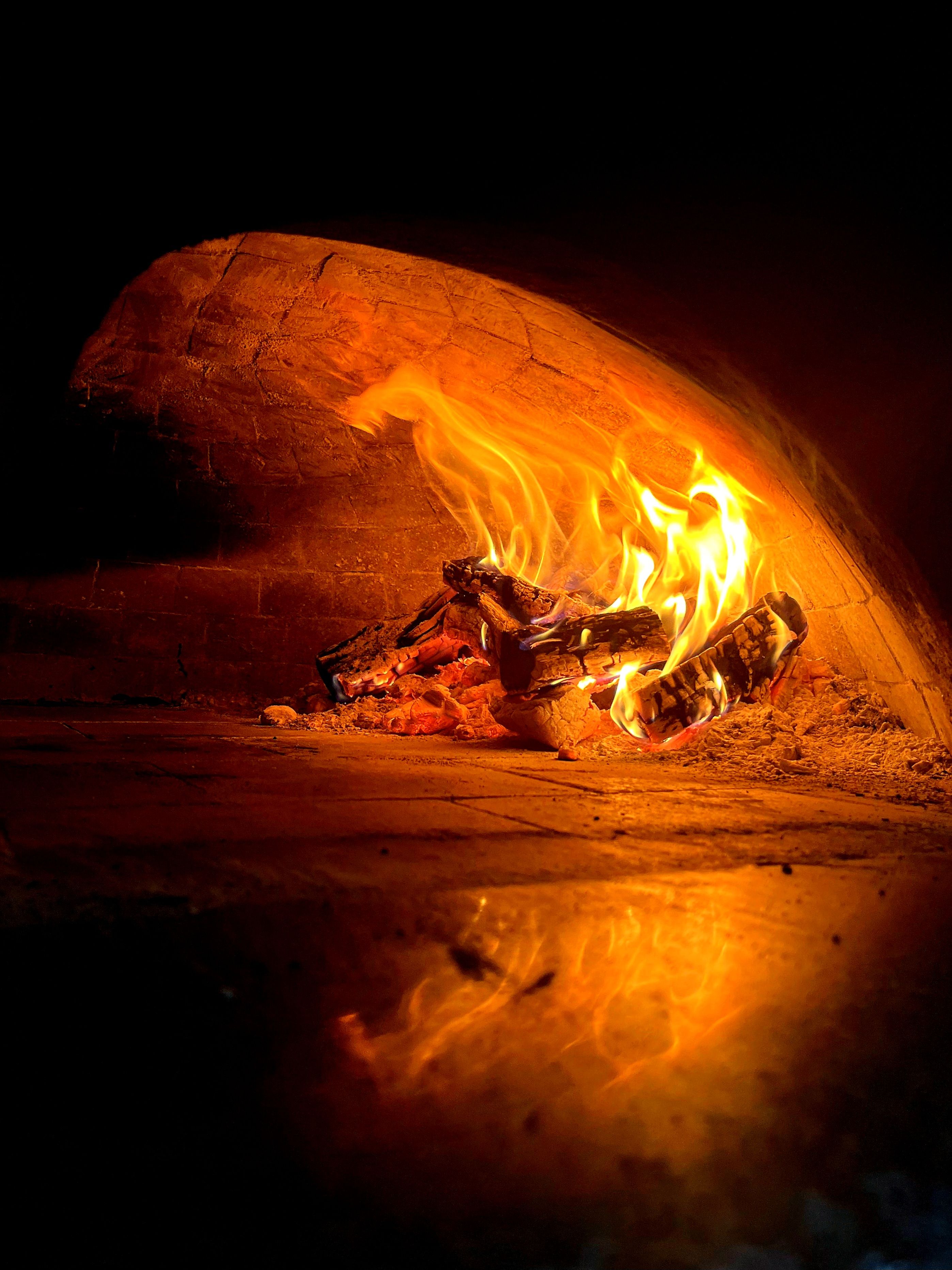 A wood-fired oven with glowing flames inside, creating a warm ambiance.
