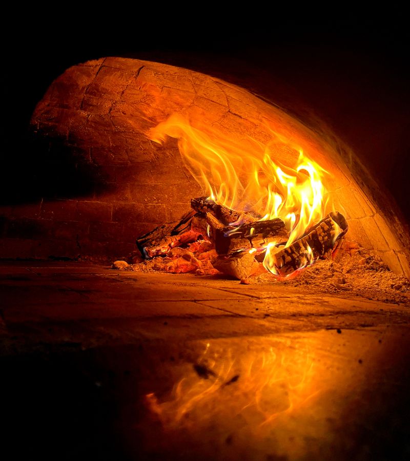 A wood-fired oven with glowing flames inside, creating a warm ambiance.