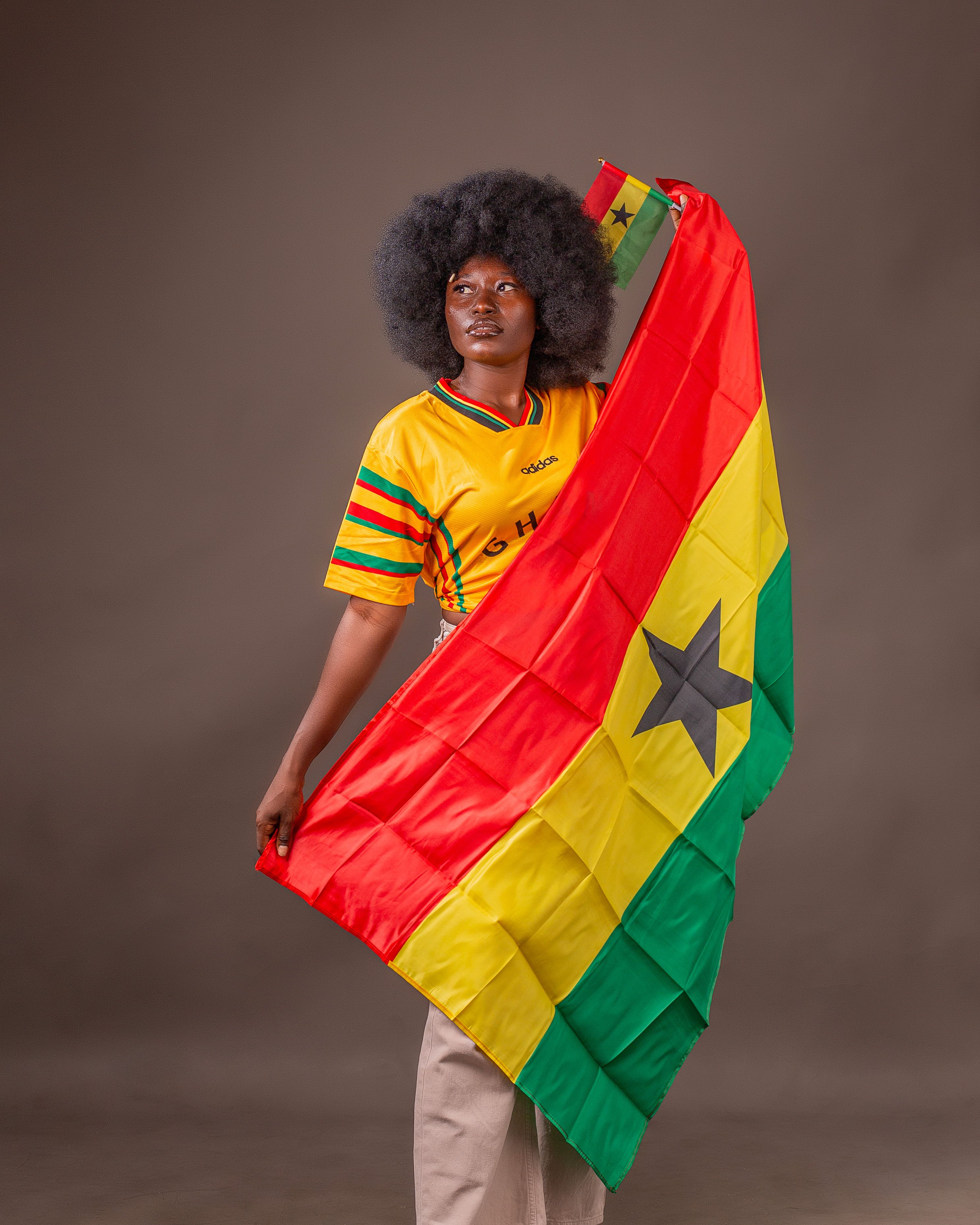 A person in vibrant attire holds the Ghana flag with pride.