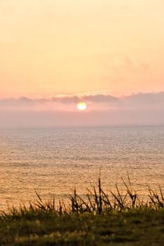 Tranquil sunrise over a calm ocean with gentle waves and soft colors.