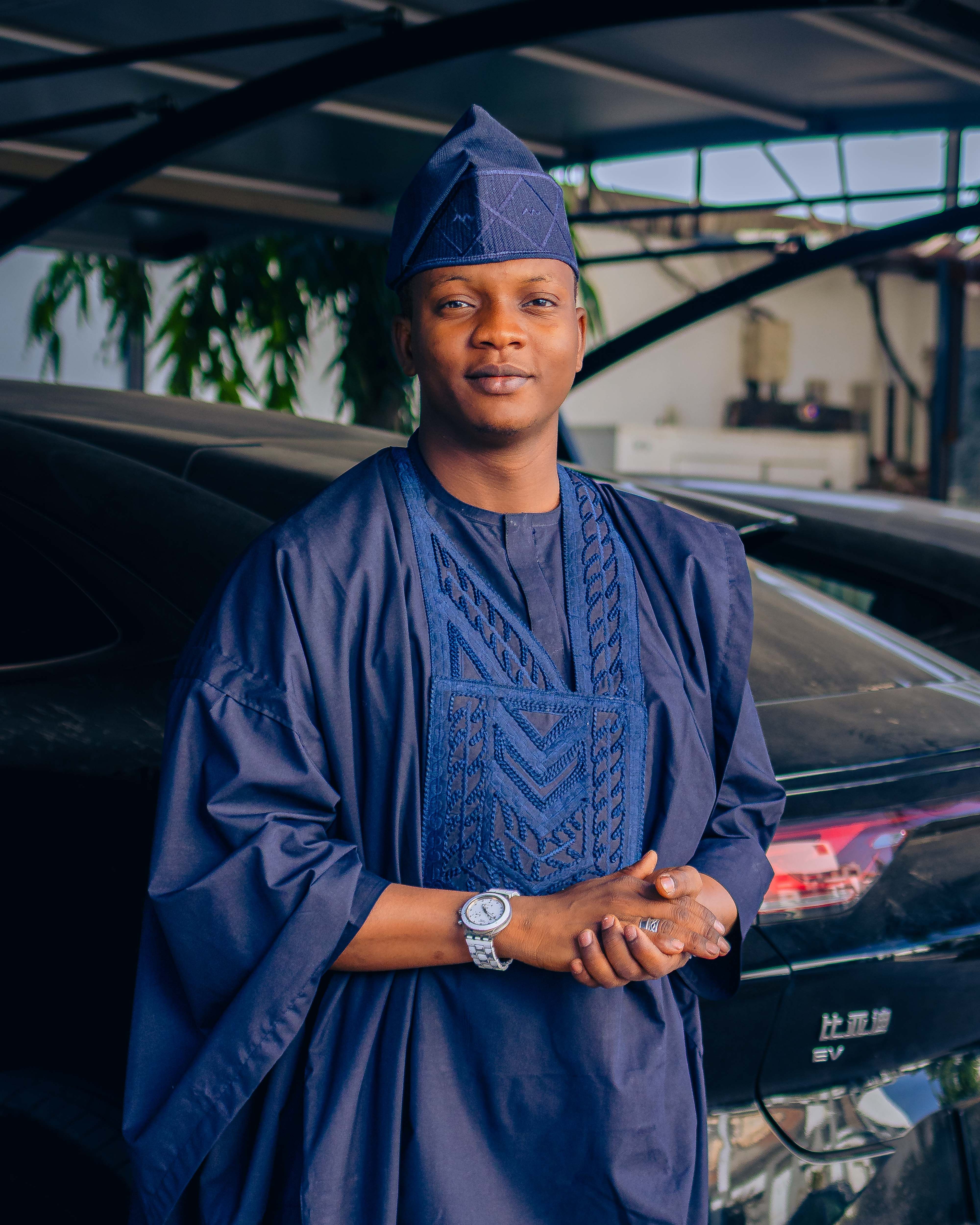 Elegant man wearing a traditional outfit poses confidently indoors, showcasing cultural fashion.
