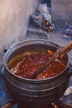 A close-up of a large pot of jollof rice being cooked outdoors in Nigeria.