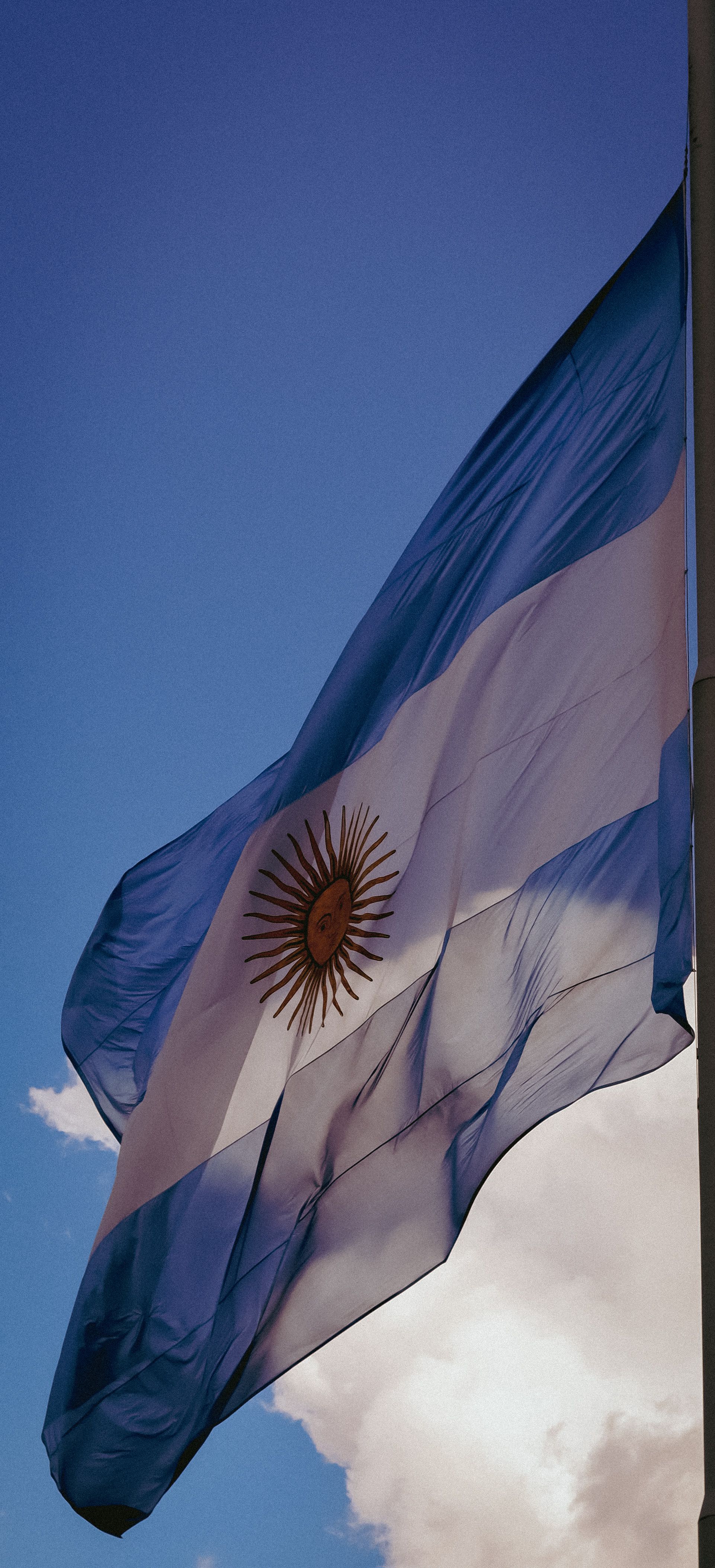 A vibrant Argentinian flag flutters gracefully against a clear blue sky, symbolizing national pride.