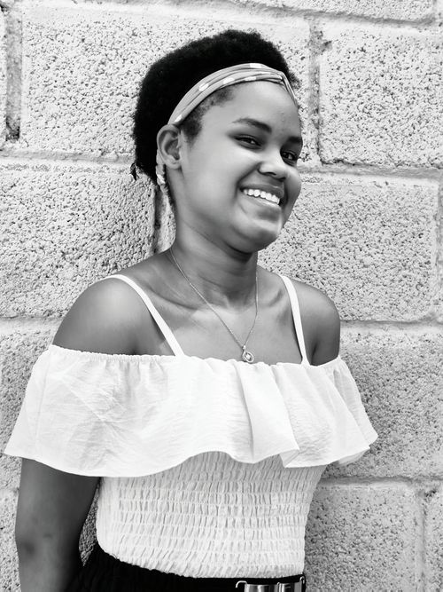 Free Black and white portrait of a young woman smiling against a textured brick wall. Stock Photo