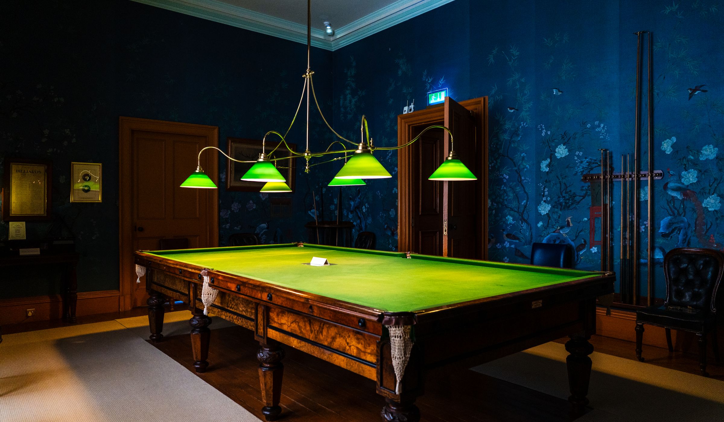 Championship snooker table illuminated under focused overhead spotlighting