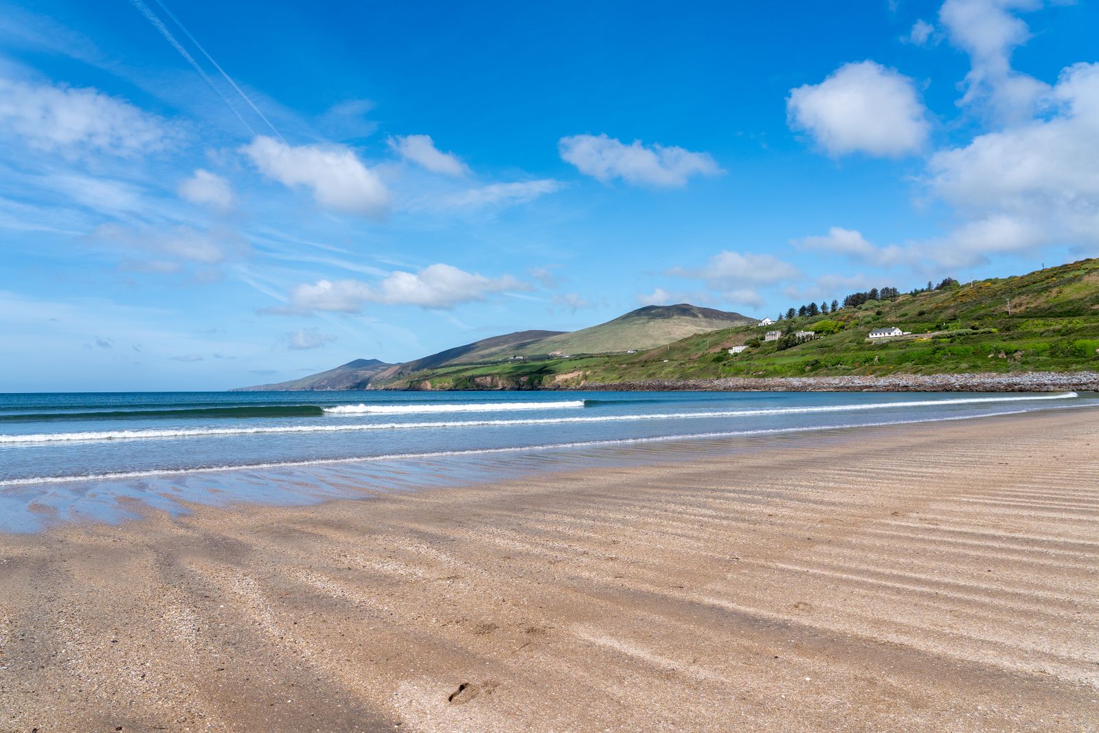 A beach with rolling waves and green hills on the Dingle Peninsula