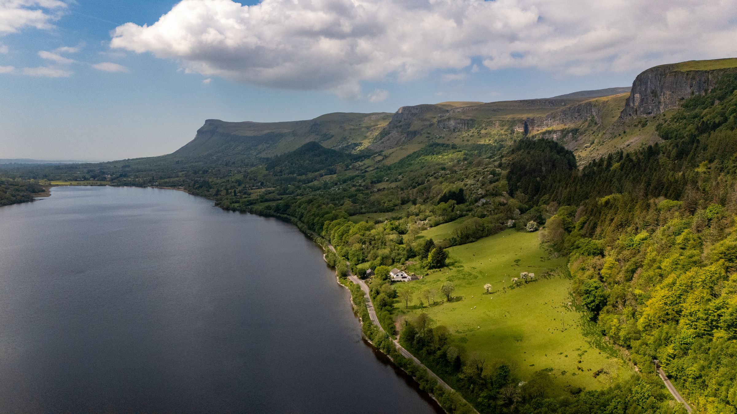 A aerial view of an Irish landscape with green hills and a lake