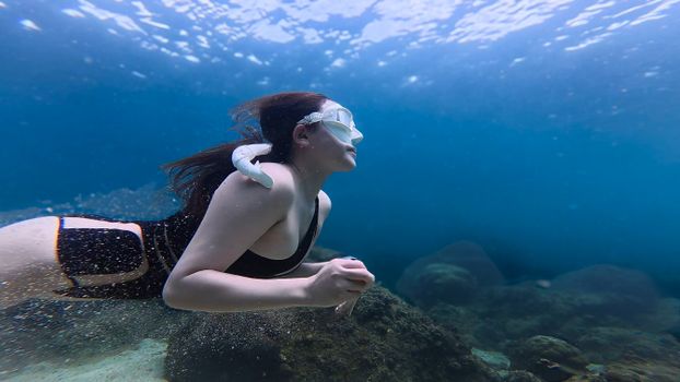 A woman snorkels underwater in the clear ocean, exploring marine life.