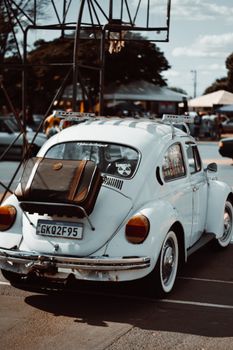 A classic white Volkswagen Beetle with luggage parked on a sunny day.