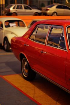 Classic vintage cars parked on an urban street, beautifully lit by the warm glow of sunset.