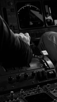 Monochrome photo of a pilot's hand adjusting controls in an aircraft cockpit, highlighting aviation technology.