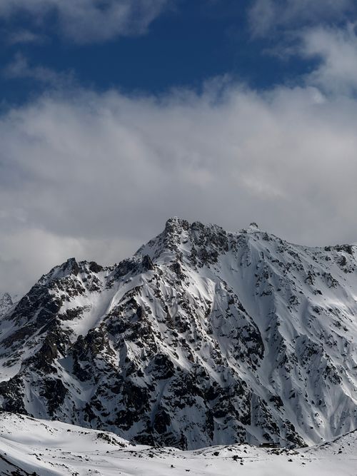 Free Stunning view of snow-covered peaks in the Caucasus Mountains under a cloudy sky, perfect for winter travel inspiration. Stock Photo