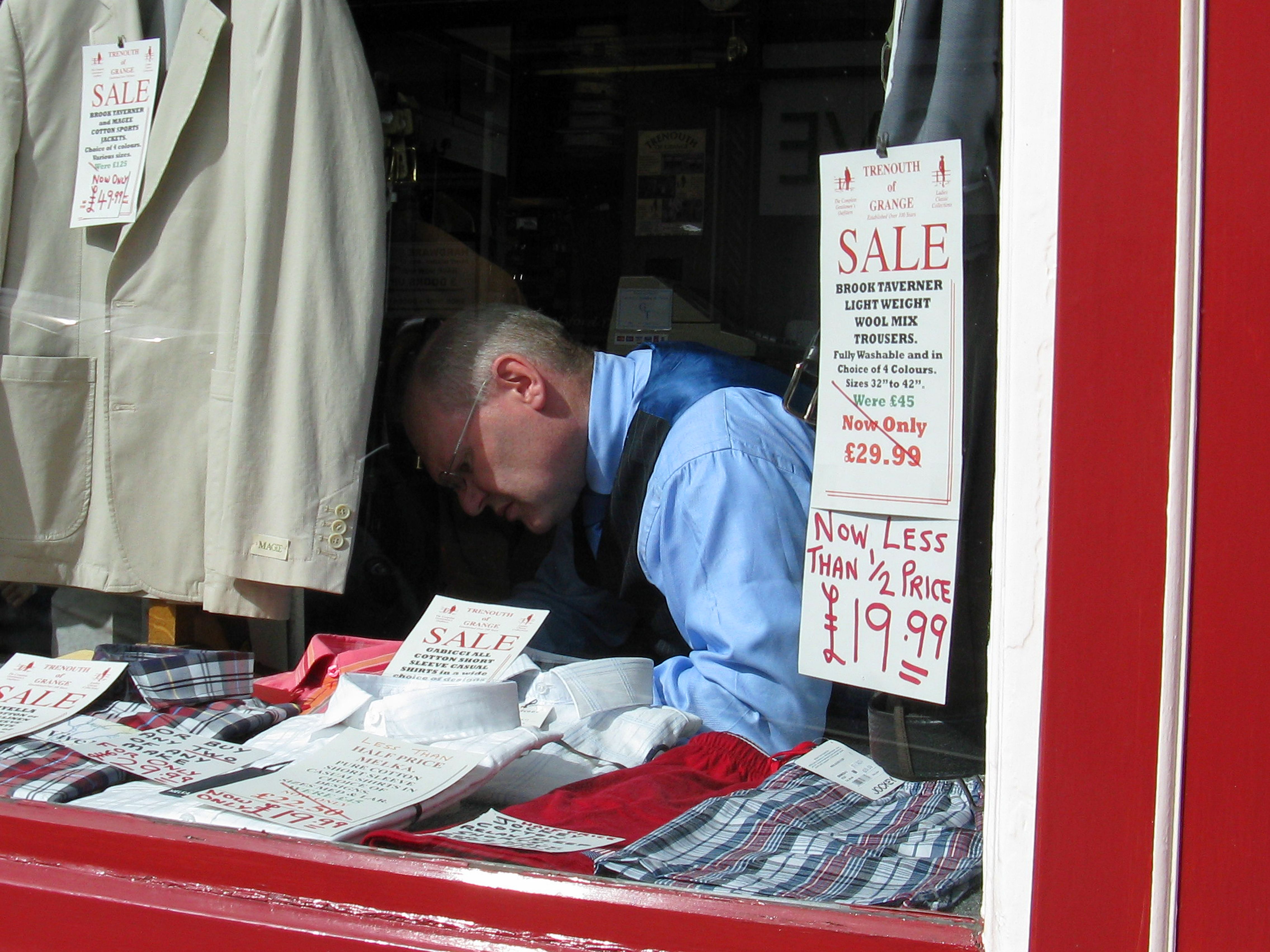 Shopkeeper Arranging Storefront Display in Sale · Free Stock Photo