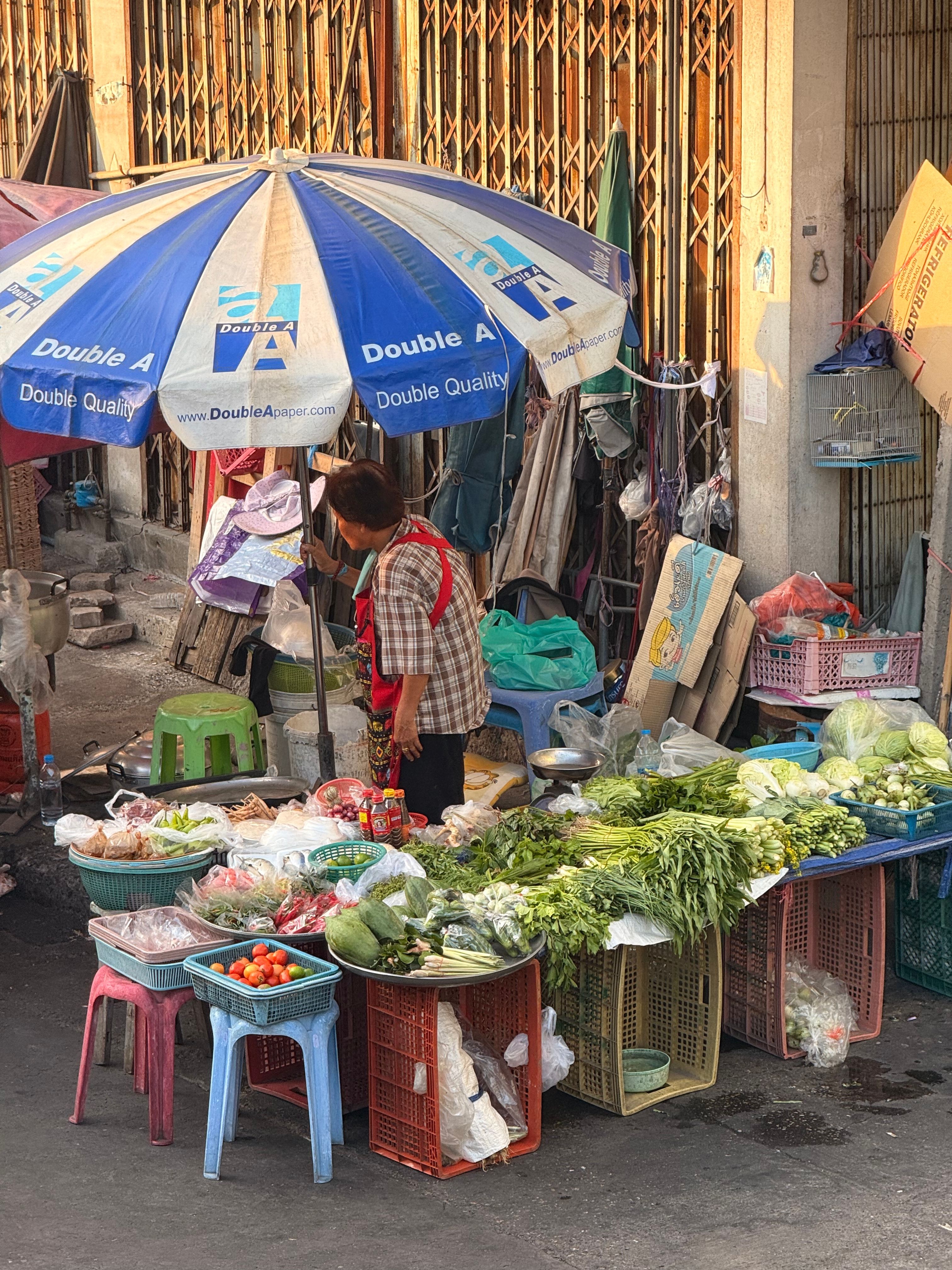 Street vendor selling fresh vegetables and produce at an outdoor Thai market