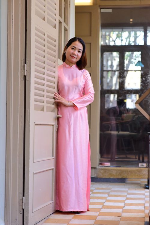 Free Woman in traditional pink Ao Dai standing in a doorway, indoors. Stock Photo