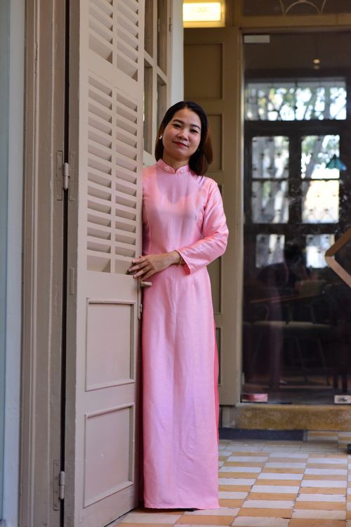Free Woman in a pink traditional dress stands in an open doorway, indoors. Stock Photo