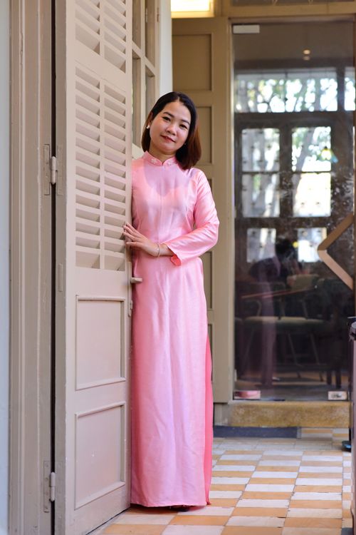 Free Asian woman in traditional pink dress standing by a wooden doorway indoors. Stock Photo