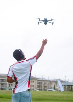 Man controlling a drone in an open field, showcasing modern technology outdoors.