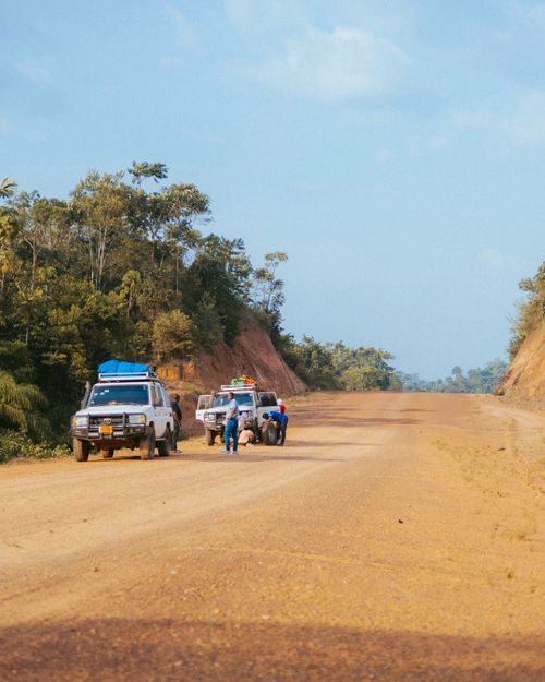 Free 4x4 vehicles on a remote dirt road in Monrovia, Liberia, capturing travel essence. Stock Photo