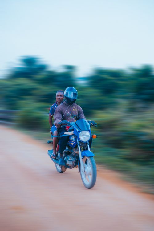 Free A motorcyclist with a passenger rides swiftly along a rural road in Monrovia, Liberia. Stock Photo
