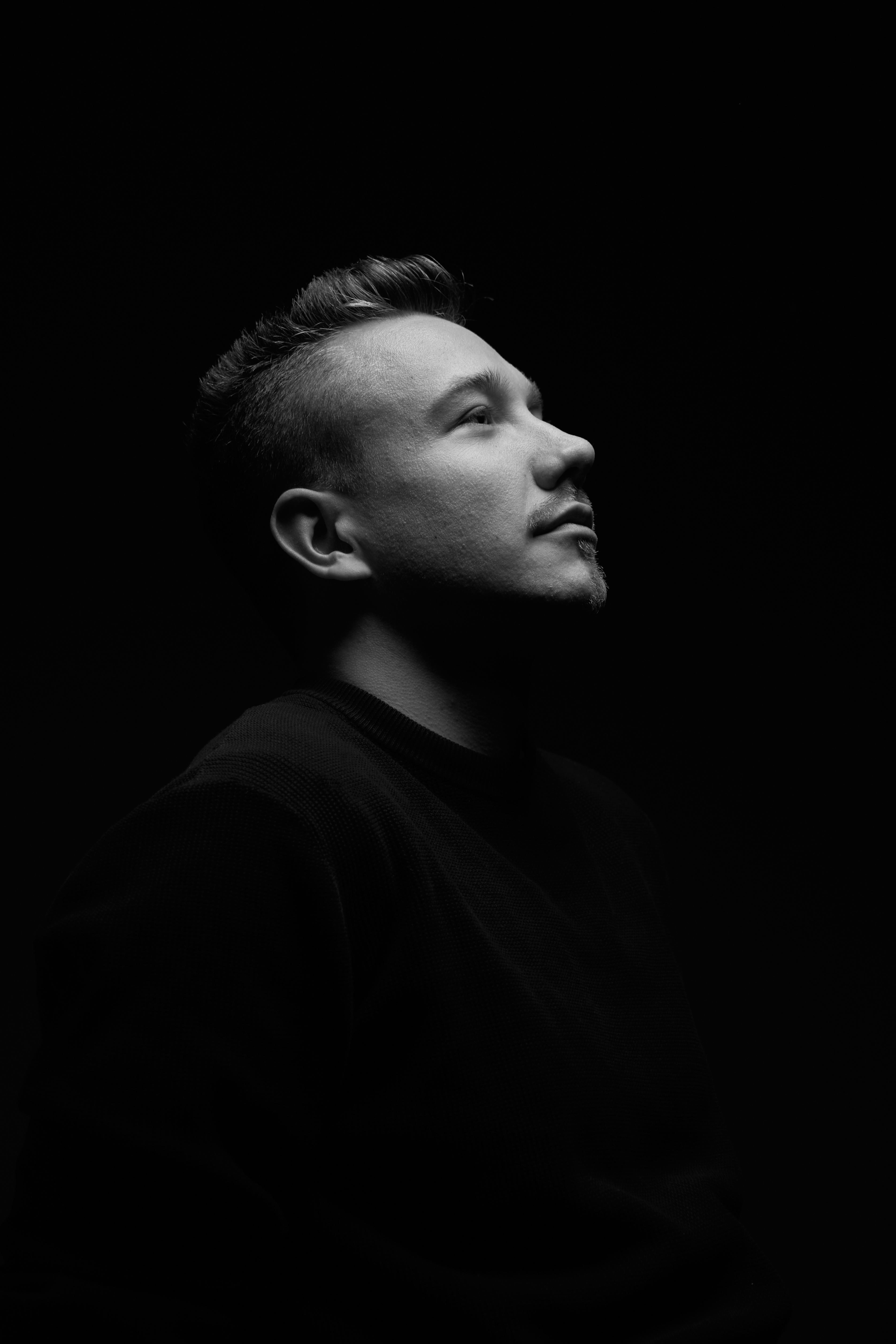 Dramatic black and white portrait capturing an introspective moment of a man looking upwards.