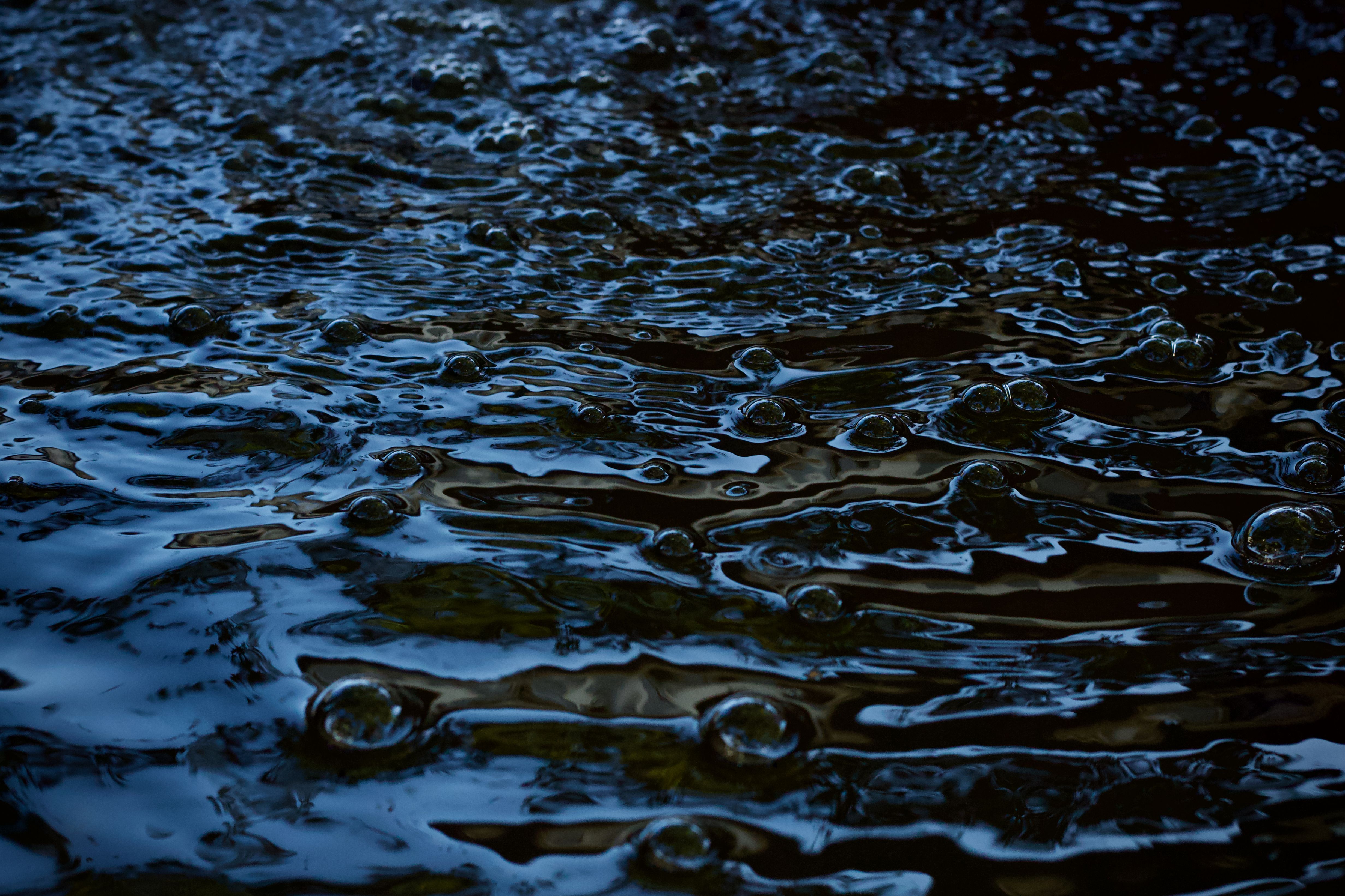 Dark Rippling Water Surface with Bubbles · Free Stock Photo