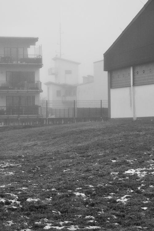Free A foggy urban scene with modern buildings partially hidden by dense mist. Stock Photo
