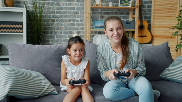 A mother and daughter bonding over video games in a cozy living room setting.
