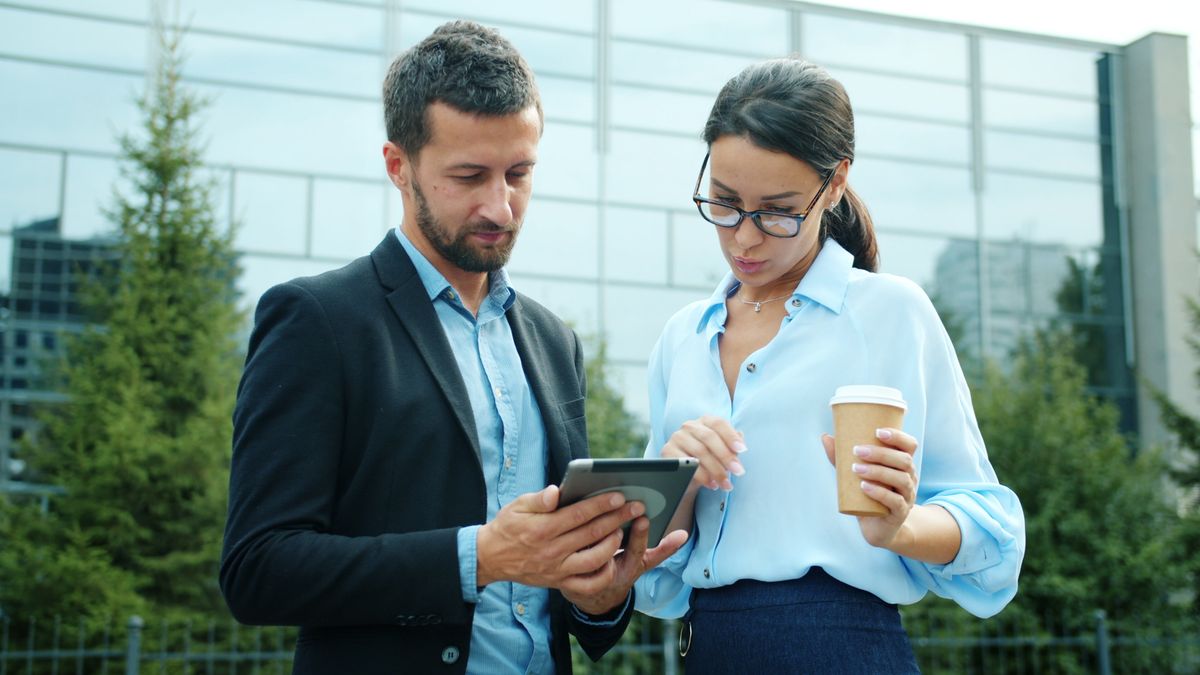 Dua profesional menggunakan tablet saat bekerja di luar kantor
