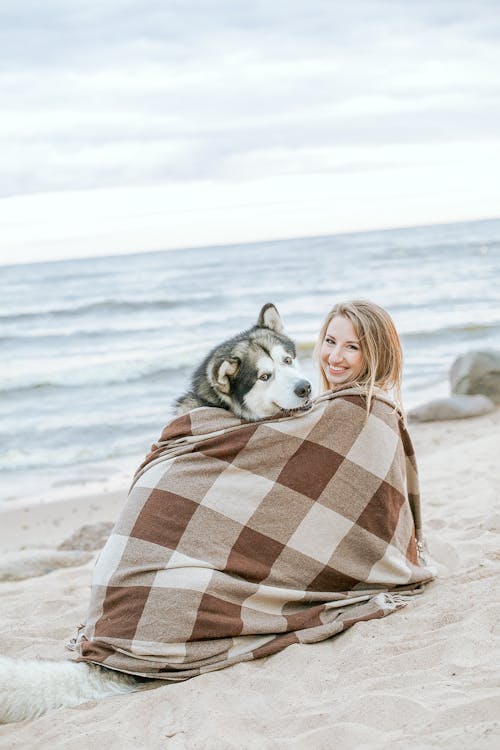 Woman in Brown and White Plaid Scarf Sitting on Beach