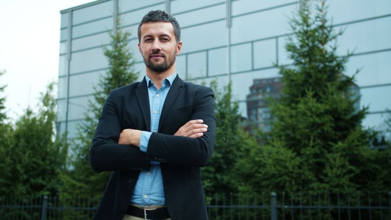 A confident professional standing with arms crossed in an urban setting