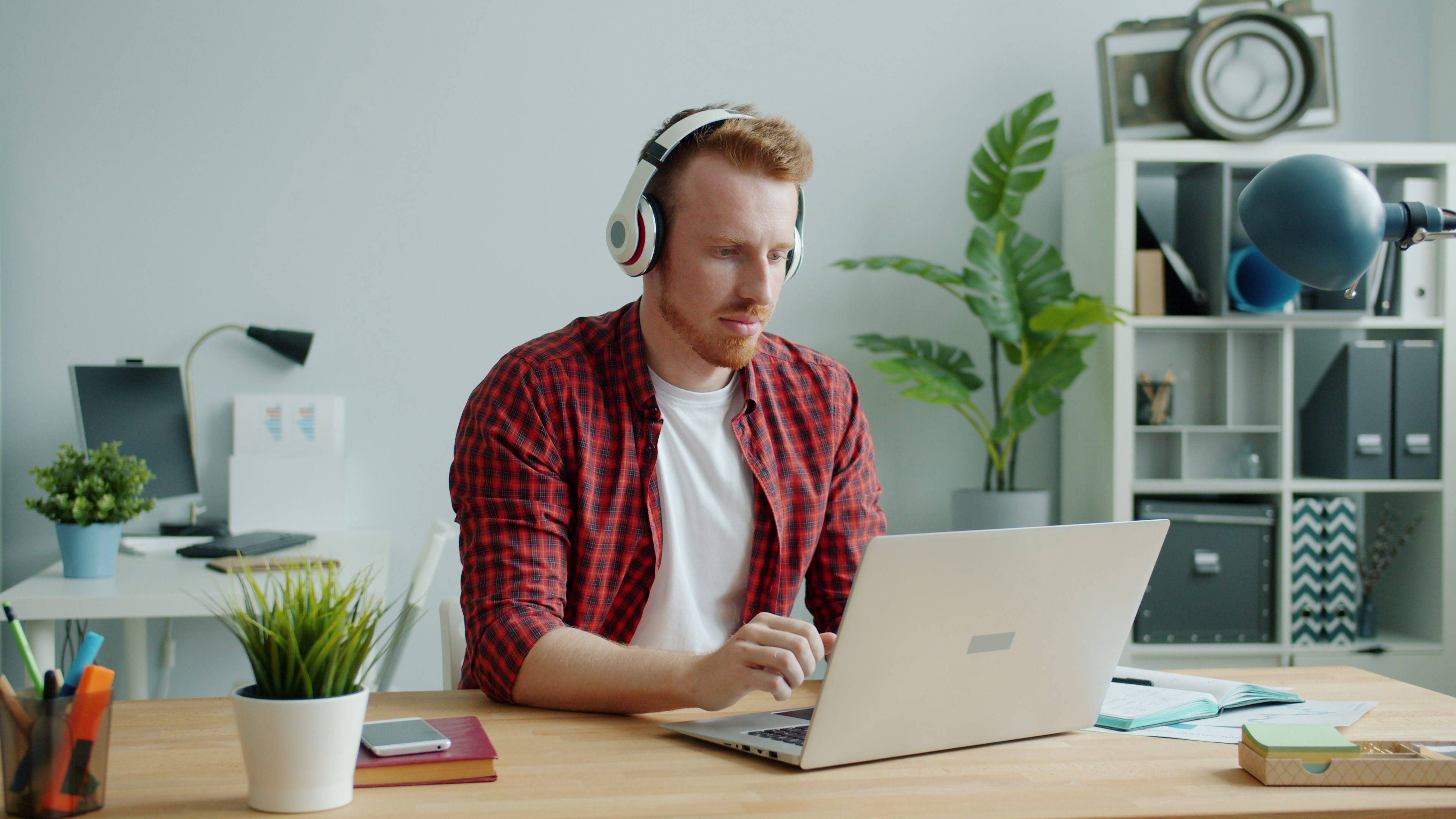 Young Man Working Remotely with Laptop and Headphones · Free Stock Photo