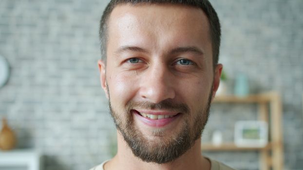Portrait of a smiling man indoors with a blurred brick wall in the background.