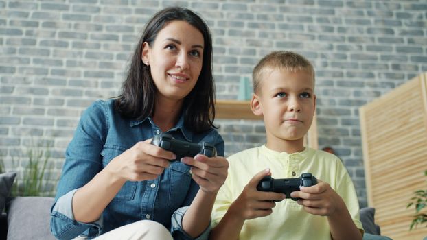 Mother and son enjoy gaming together indoors, creating a joyful bond.