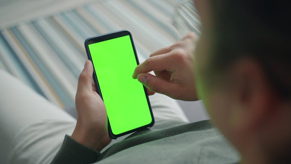 How Solo Creators Automate Instagram Posting with Buffer and Zapier Close-up of a person using a smartphone with a green screen indoors.