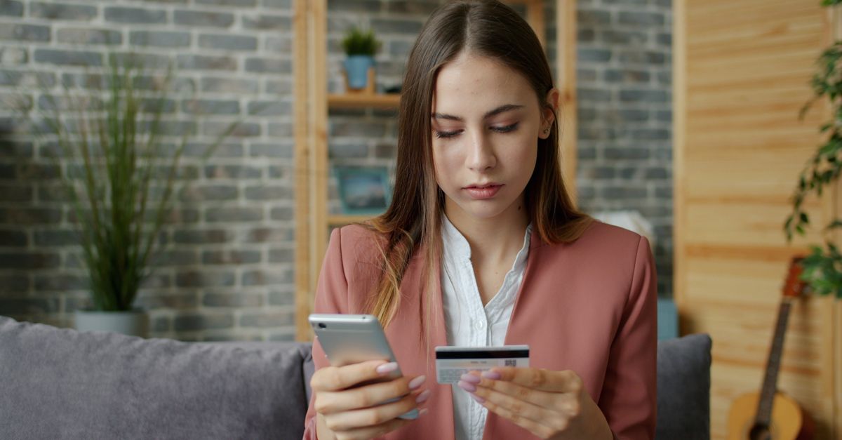 Hispanic woman comparing financial apps on smartphone at coffee shop