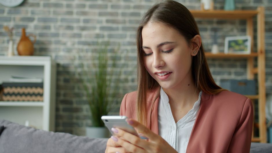 Casual young woman using smartphone at home, working or socializing.