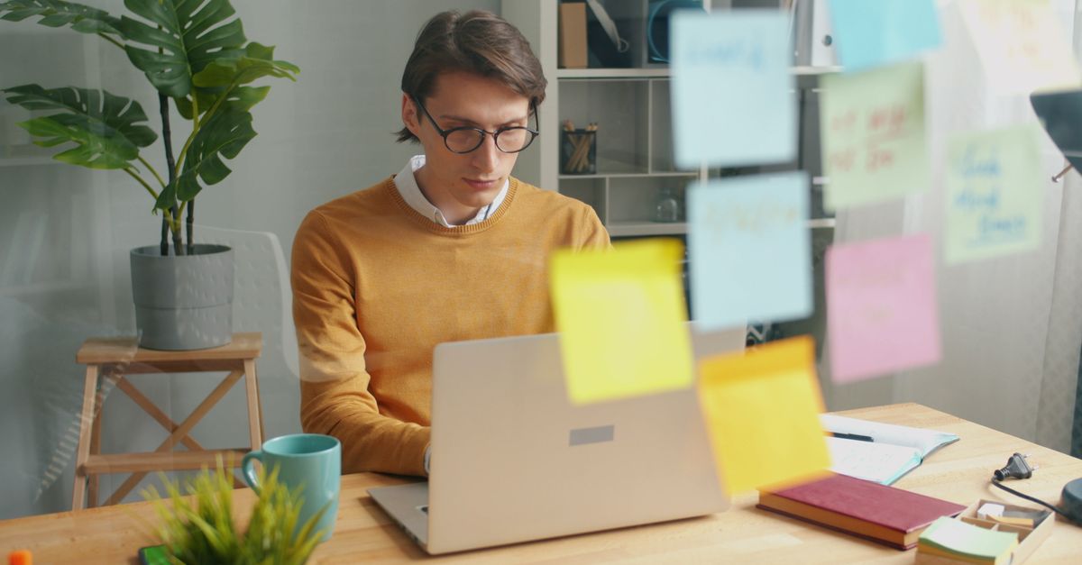 founder working late on laptop in a modest home office with coffee and sticky notes