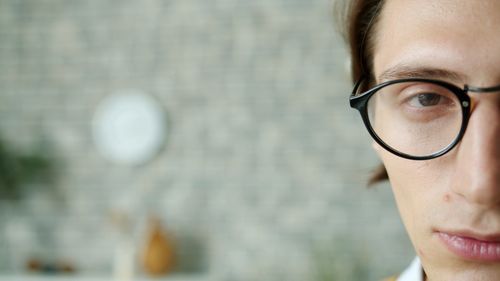Free Half-face close-up of a young man wearing glasses indoors. Stock Photo