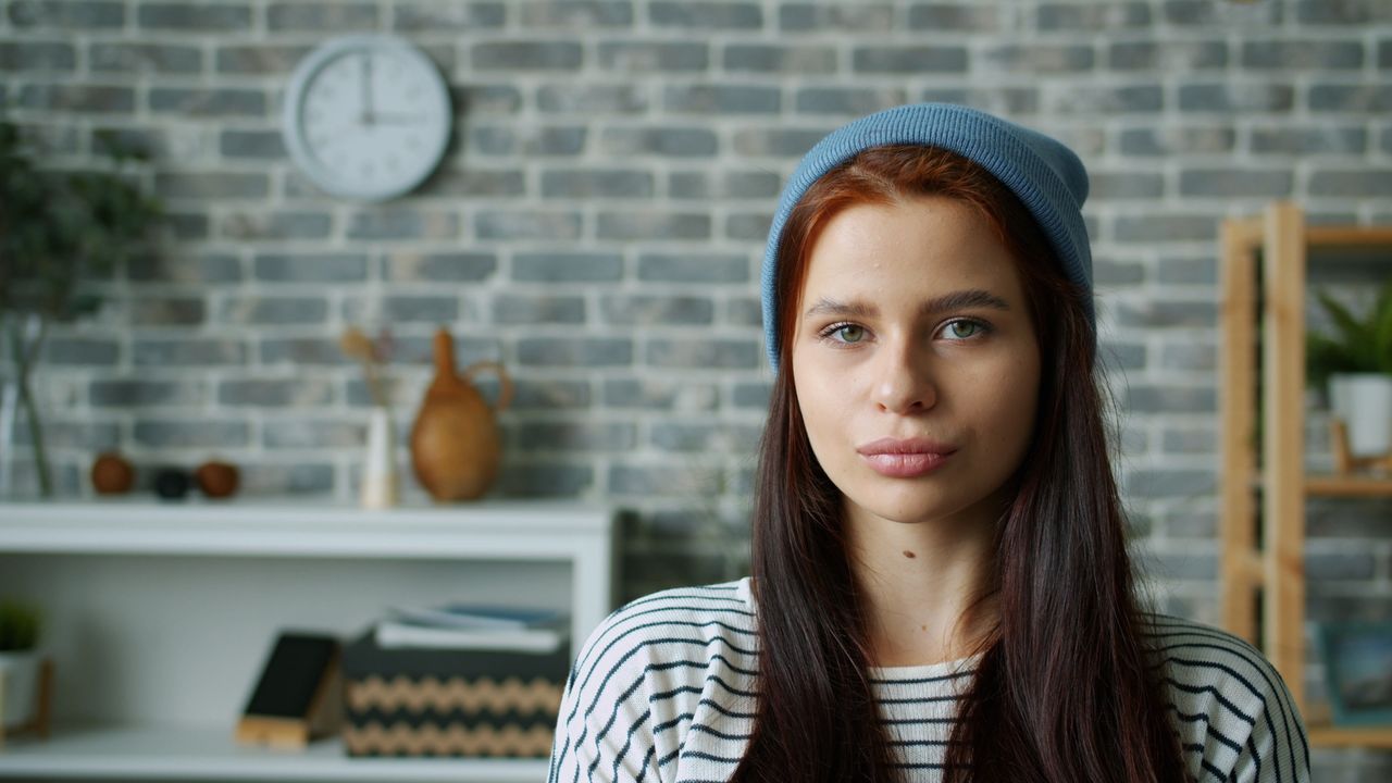 portrait of a young woman wearing a beanie indoors with a stylish bric