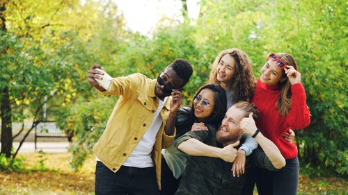 Free Group of diverse friends taking a selfie in a park during autumn. Stock Photo