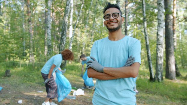 Group of diverse volunteers cleaning up litter in a forest, promoting environmental awareness.