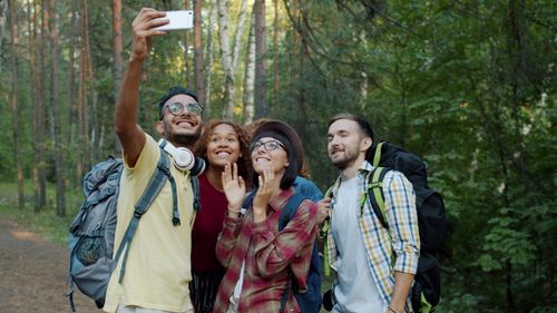 Free Happy group of young adults capturing a selfie during a forest hike. Stock Photo