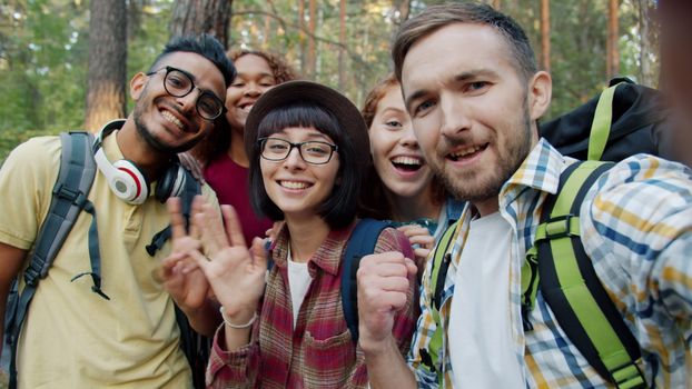 Group of friends enjoying a hike, taking a selfie in a forest. Smiling and cheerful.