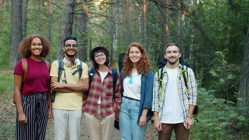Free Diverse group of friends smiling and hiking through a lush forest path. Stock Photo