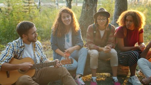 Free Group of friends hanging out in nature, enjoying music and company. Stock Photo