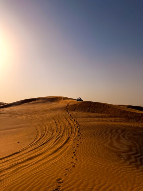 Free Explore the stunning desert dunes of Dubai with footprints and tire tracks under the bright sun. Stock Photo