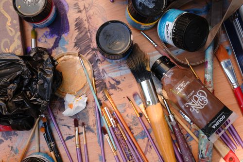Free Flat lay of artist supplies with brushes and paints creating a vibrant, chaotic scene. Stock Photo