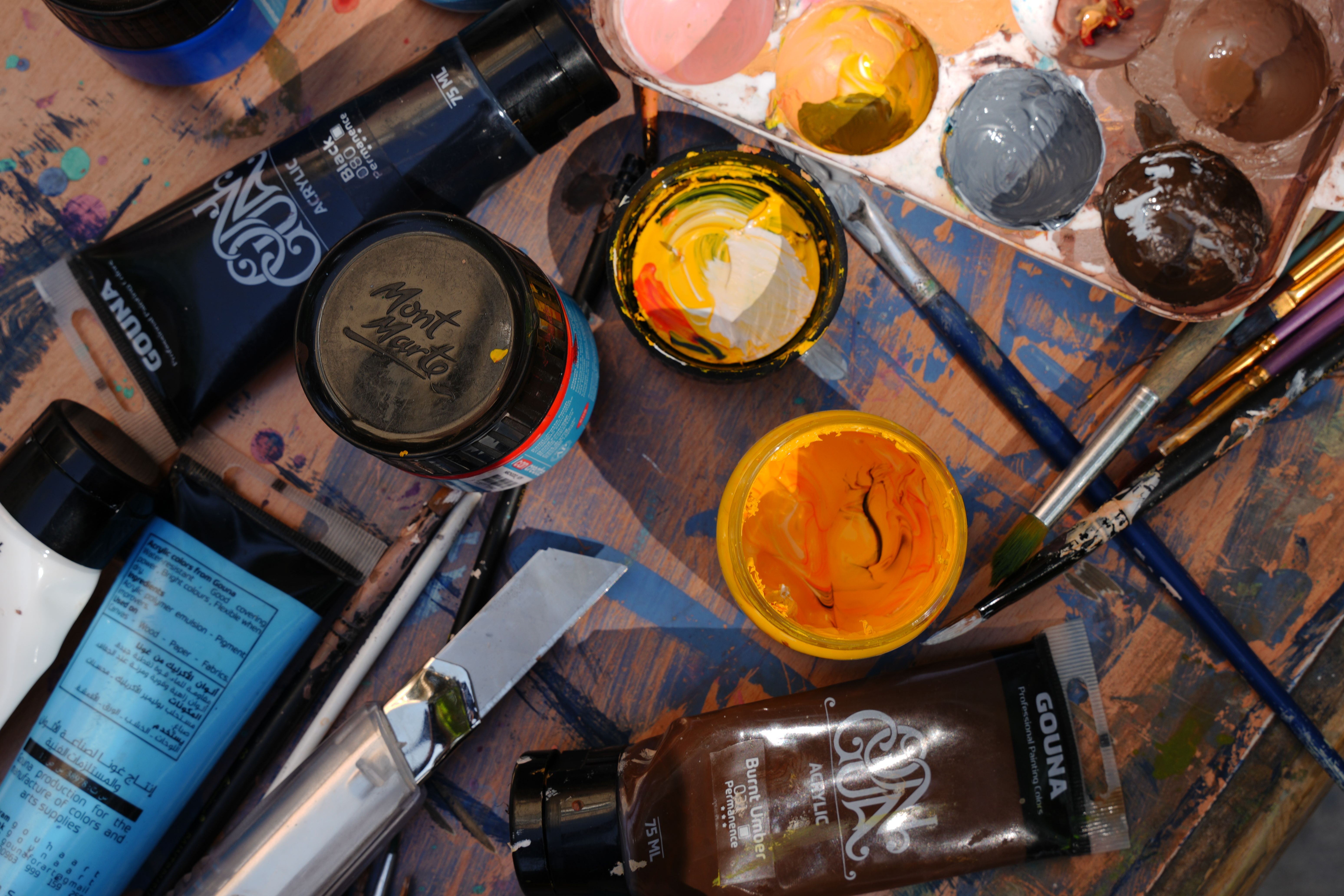 Colorful artist's workspace with paint tubes, brushes, and palette, captured from above.